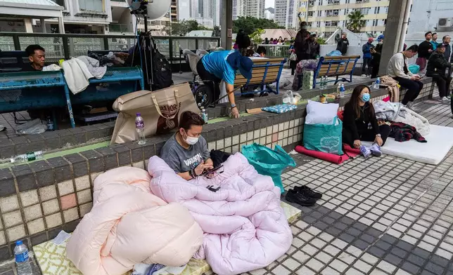Residents rest nearby in the aftermath of a fire which broke out Wednesday at Wang Fuk Court, a residential estate in the Tai Po district of Hong Kong's New Territories, Thursday, Nov. 27, 2025. (AP Photo/Chan Long Hei)
