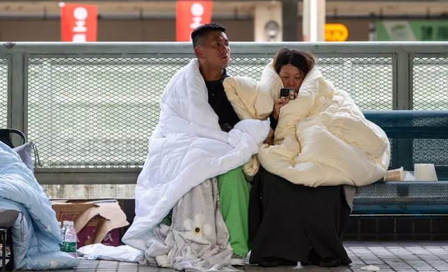 Residents rest at the fire scene at Wang Fuk Court, a residential estate in the Tai Po district of Hong Kong's New Territories, Thursday, Nov. 27 2025. (AP Photo/Chan Long Hei)