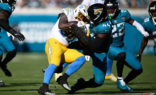 Los Angeles Chargers running back Kimani Vidal (30) is tackled by Jacksonville Jaguars defensive end Travon Walker (44) during the first half of an NFL football game, Sunday, Nov. 16, 2025, in Jacksonville, Fla. (AP Photo/Phelan M. Ebenhack)