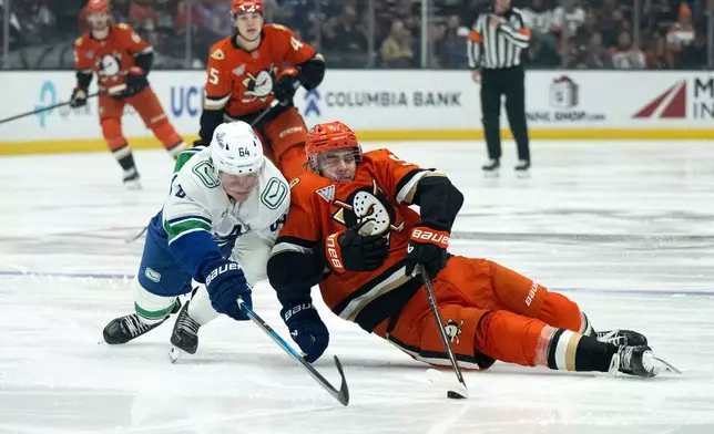 Anaheim Ducks center Leo Carlsson (91) and Vancouver Canucks center David Kampf (64) vie for the puck during the first period of an NHL hockey game, Wednesday, Nov. 26, 2025, in Anaheim, Calif. (AP Photo/Kyusung Gong)