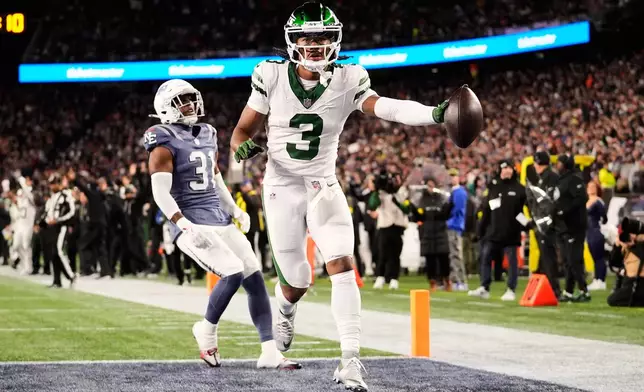 New York Jets' John Metchie III scores a touchdown past. New England Patriots' Craig Woodson during the second half of an NFL football game, Thursday, Nov. 13, 2025, in Foxborough, Mass. (AP Photo/Robert F. Bukaty)