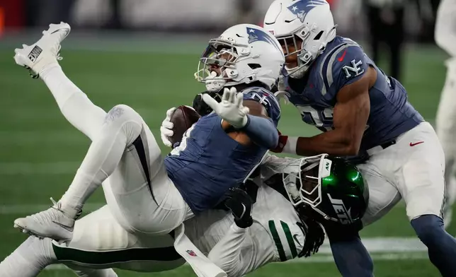 New York Jets cornerback Jarvis Brownlee Jr., bottom, takes down New England Patriots' Stefon Diggs during the first half of an NFL football game, Thursday, Nov. 13, 2025, in Foxborough, Mass. (AP Photo/Charles Krupa)