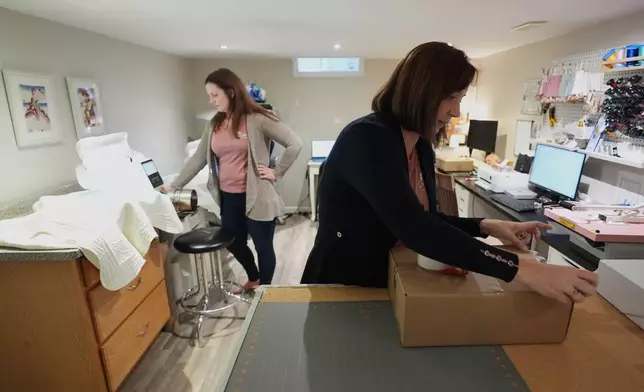 Fran Poirier, right, and her sister, Sue Bacarro, left, fill orders at their Etsy shop, Digi Wildflowers, Thursday, Oct. 30, 2025, in Windsor, Ontario, Canada. (AP Photo/Paul Sancya)