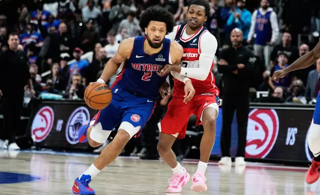 Detroit Pistons guard Cade Cunningham, left, drives against Washington Wizards guard Bub Carrington during overtime in an NBA basketball game Monday, Nov. 10, 2025, in Detroit. (AP Photo/Ryan Sun)