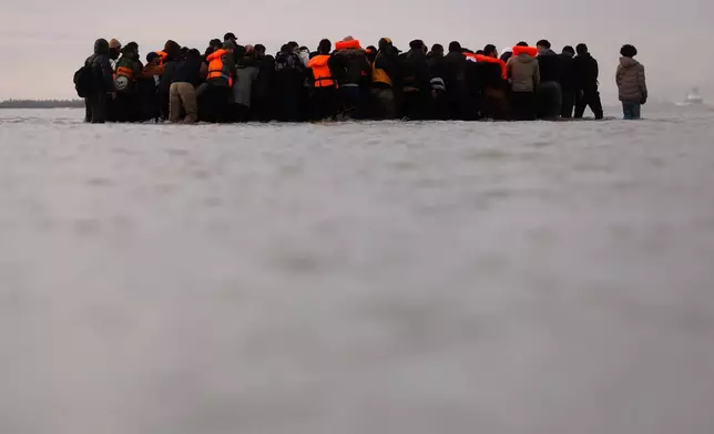Migrants push a small boat in an attempt to reach Britain, Thursday, Nov. 6, 2025 in Gravelines, northern France. (AP Photo/Jean-Francois Badias)