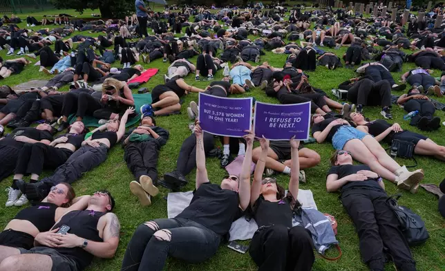 Participants hold signs while lying on the ground during a gender-based violence protest at the forecourt of the botanical gardens in Johannesburg, South Africa, Friday, Nov. 21, 2025. (Misper Apawu)