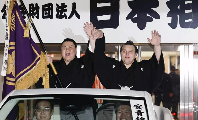 Ukrainian Aonishiki, right, waves during a parade after winning the Kyushu Grand Sumo Tournament in Fukuoka, western Japan, Sunday, Nov. 23, 2025. (Kyodo News via AP)