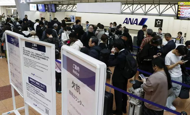 Passengers wait in line at All Nippon Airways' counter at Haneda airport in Tokyo Saturday, Nov. 29, 2025. A sign, right, reads " Flight cancellation counter." (Takahiko Kanbara/Kyodo News via AP)