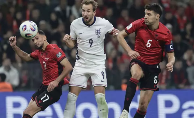 England's Harry Kane, center, scores his side's second goal as Albania's Naser Aliji, left, and Berat Djimsiti try to stop him during the World Cup 2026 group K qualifying soccer match between Albania and England, in Tirana, Albania, Sunday, Nov. 16, 2025.(AP Photo/Vlasov Sulaj)