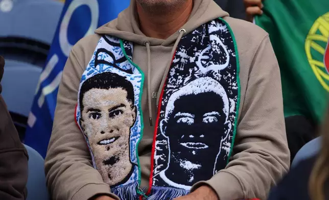 A fan on the stands wears a scarf with a picture of Portugal's Cristiano Ronaldo before a World Cup 2026 group F qualifying soccer match between Portugal and Armenia in Porto, Portugal, Sunday, Nov. 16, 2025. (AP Photo/Luis Vieira)