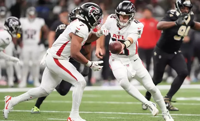 Atlanta Falcons quarterback Kirk Cousins hands off to running back Bijan Robinson against the New Orleans Saints in the second half of an NFL football game, Sunday, Nov. 23, 2025, in New Orleans. (AP Photo/Gerald Herbert)