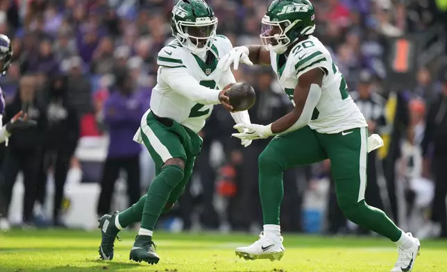 New York Jets quarterback Tyrod Taylor (2) hand off to running back Breece Hall (20) during the first half of an NFL football game against the Baltimore Ravens, Sunday, Nov. 23, 2025, in Baltimore. (AP Photo/Stephanie Scarbrough)