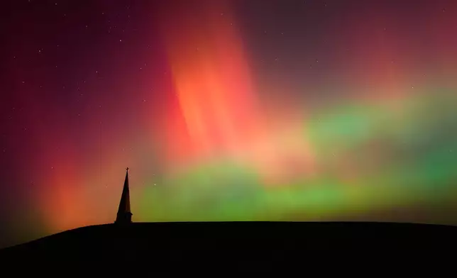 The northern lights fill the sky behind the Saint Joseph the Woodworker Shrine Tuesday, Nov. 11, 2025, near Valley Falls, Kan. (AP Photo/Charlie Riedel)