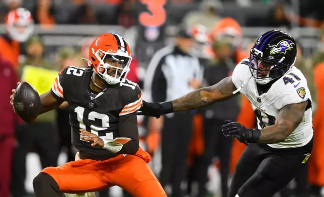 Cleveland Browns quarterback Shedeur Sanders (12) is pressured out of the pocket by Baltimore Ravens' Dre'Mont Jones (41) in the second half of an NFL football game in Cleveland, Sunday, Nov. 16, 2025. (AP Photo/David Richard)