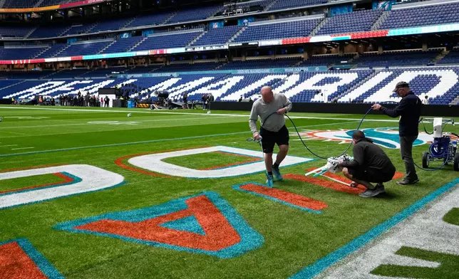 Workers prepare the field at the Santiago Bernabeu stadium ahead of an NFL game between the Miami Dolphins and Washington Commanders in Madrid, Spain, Friday, Nov. 14, 2025. (AP Photo/Steve Luciano)