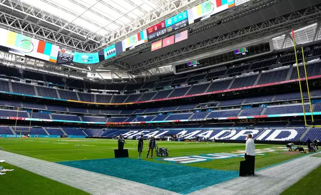 Workers prepare the field at the Santiago Bernabeu stadium ahead of an NFL game between the Miami Dolphins and Washington Commanders in Madrid, Spain, Friday, Nov. 14, 2025. (AP Photo/Steve Luciano)