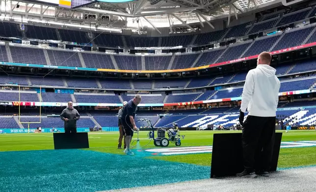 Workers prepare the field at the Santiago Bernabeu stadium ahead of an NFL game between the Miami Dolphins and Washington Commanders in Madrid, Spain, Friday, Nov. 14, 2025. (AP Photo/Steve Luciano)