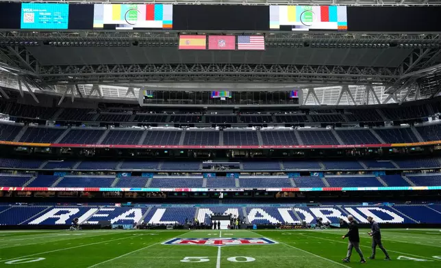 Workers prepare the field at the Santiago Bernabeu stadium ahead of an NFL game between the Miami Dolphins and Washington Commanders in Madrid, Spain, Friday, Nov. 14, 2025. (AP Photo/Steve Luciano)