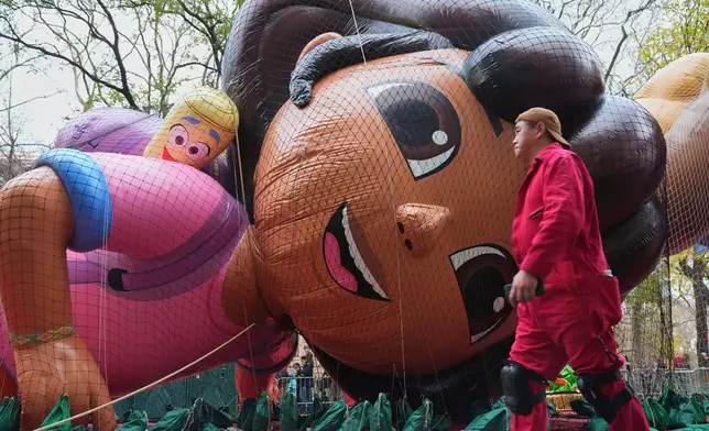 A volunteer passes the Nickelodeon's Dora balloon during the balloon inflation for the 99th Macy's Thanksgiving Day Parade Wednesday, Nov. 26, 2025, in New York. (AP Photo/Frank Franklin II)