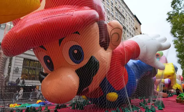 People pass Mario balloon during inflation for the 99th Macy's Thanksgiving Day Parade Wednesday, Nov. 26, 2025, in New York. (AP Photo/Frank Franklin II)