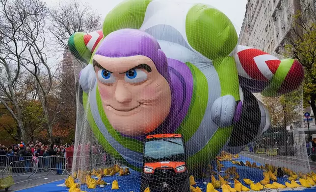 People pass Buzz Lightyear during the balloon inflation for the 99th Macy's Thanksgiving Day Parade, Wednesday, Nov. 26, 2025, in New York. (AP Photo/Frank Franklin II)