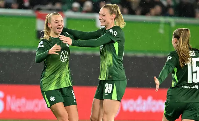 Wolfsburg's Ella Peddemors, left, celebrates scoring with Sarai Linder and Janou Levels, right, during the Women's Champions League soccer match between VfL Wolfsburg and Manchester United in Wolfsburg, Germany, Wednesday Nov. 19, 2025. (Swen Pförtner/dpa via AP)