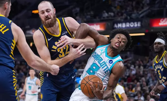 Indiana Pacers center Jay Huff (32) and Charlotte Hornets guard Collin Sexton (8) get tangled as they fight for a rebound during the first half of an NBA basketball game in Indianapolis, Wednesday, Nov. 19, 2025. (AP Photo/Michael Conroy)
