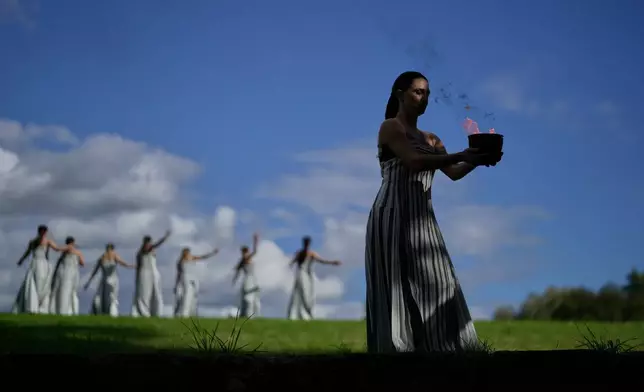 Actress Mary Mina, playing the high priestess holds a pot with the flame during a rehearsal ahead of the flame lighting for the Milan Cortina 2026 Winter Olympics, at the Ancient Olympia site, Greece, Monday, Nov. 24, 2025. (AP Photo/Petros Giannakouris)