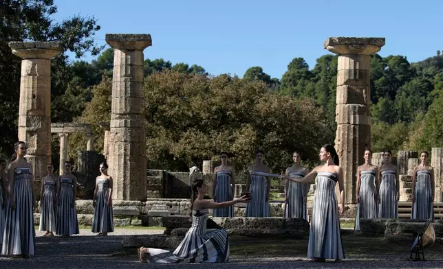 Actor Mary Mina playing the role of high priestess, right, performs during a rehearsal ahead of the flame lighting for the Milan Cortina 2026 Winter Olympics, at the Ancient Olympia site, Greece, Monday, Nov. 24, 2025. (AP Photo/Thanassis Stavrakis)