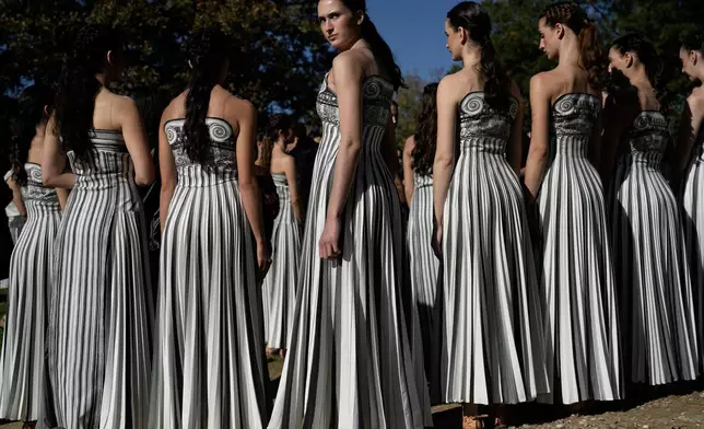 Performers playing the role of priestesses wait for the start of a rehearsal ahead of the flame lighting for the Milan Cortina 2026 Winter Olympics, at the Ancient Olympia site, Greece, Monday, Nov. 24, 2025. (AP Photo/Petros Giannakouris)