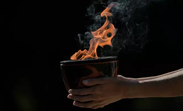 A performer holds a ceramic pot with the flame during a rehearsal ahead of the flame lighting for the Milan Cortina 2026 Winter Olympics, at the Ancient Olympia site, Greece, Monday, Nov. 24, 2025. (AP Photo/Petros Giannakouris)