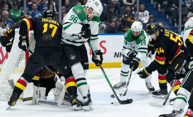 Vancouver Canucks goaltender Kevin Lankinen (32) stops Dallas Stars' Mikko Rantanen (96) and Jamie Benn (14) as Vancouver's Filip Hronek (17), and Aatu Raty (54) defend during the second period of an NHL hockey game in Vancouver, on Thursday, Nov. 20, 2025. (Ethan Cairns/The Canadian Press via AP)