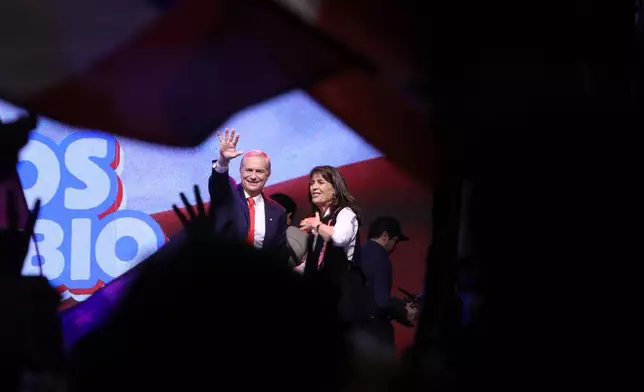 Presidential candidate Jose Antonio Kast of the Republican Party, accompanied by his wife Maria Pia Adriasola, waves to supporters after early results in the general elections in Santiago, Chile, Sunday, Nov. 16, 2025. (AP Photo/Cristobal Escobar)