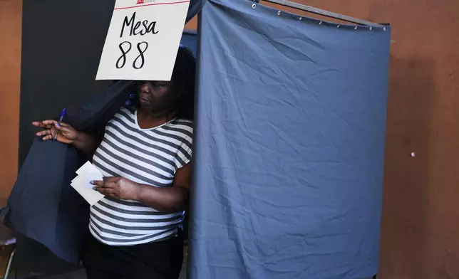 A voter holds her ballot after choosing her preferences during general elections in Santiago, Chile, Sunday, Nov. 16, 2025. (AP Photo/Natacha Pisarenko)