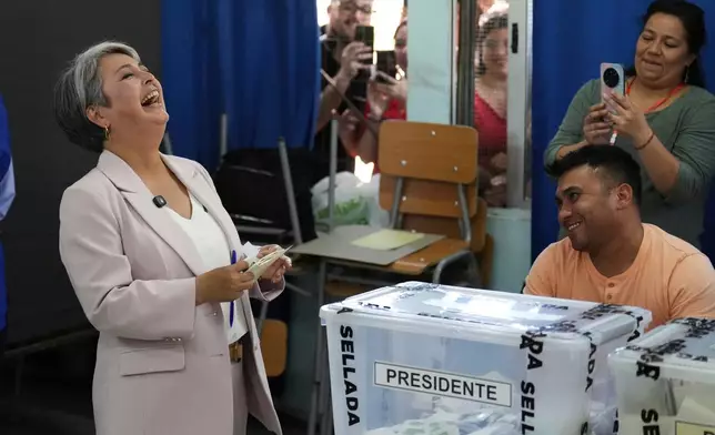 Presidential candidate Jeannette Jara of the Unidad por Chile coalition laughs while holding her ballot during general elections in Santiago, Chile, Sunday, Nov. 16, 2025. (AP Photo/Natacha Pisarenko)