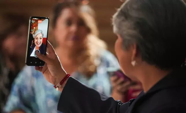 Presidential candidate Jeannette Jara of the Unidad por Chile coalition records a video during a meeting with local leaders in the La Pintana neighborhood of Santiago, Chile, Monday, Nov. 17, 2025. (AP Photo/Esteban Felix)