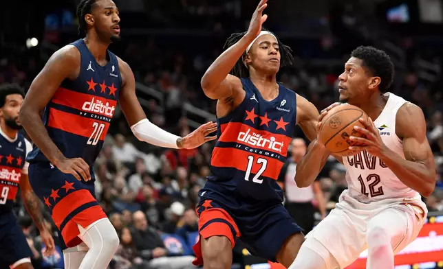 Cleveland Cavaliers forward De'Andre Hunter (12) attempts to make a shot against Washington Wizards guard Tre Johnson (12) and Wizards center Alex Sarr during the first half of an NBA Cup basketball game, Friday, Nov. 7, 2025, in Washington. (AP Photo/John McDonnell)