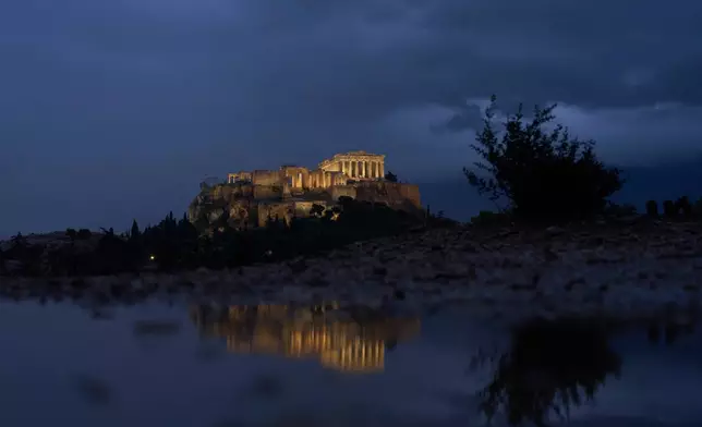 The Parthenon temple on the ancient Acropolis hill is reflected in a puddle after rainfall, Monday, Oct. 20, 2025. (AP Photo/Petros Giannakouris)