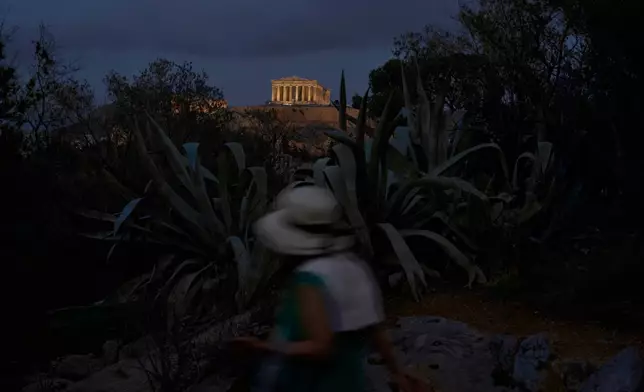 A tourist walks on Filopappos Hill with the ancient Parthenon temple atop the Acropolis in the background, in Athens, Tuesday, Oct. 21, 2025. (AP Photo/Petros Giannakouris)