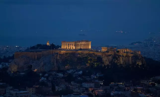A general view of Athens with the illuminated Acropolis hill and the Saronic Gulf in the background on Wednesday, Oct. 21, 2025. (AP Photo/Petros Giannakouris)