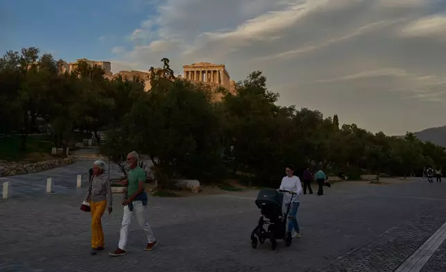 Pedestrians walk in front the Acropolis hill and the Parthenon temple in Athens, Monday, Oct. 27, 2025. (AP Photo/Petros Giannakouris)