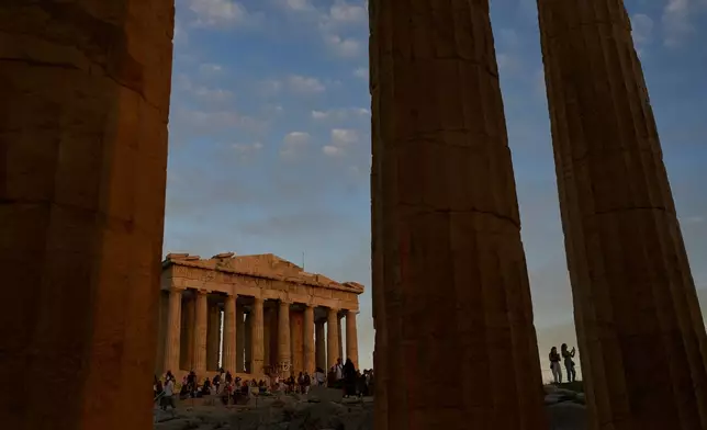 Tourists visit the Acropolis hill as the 5th century B.C. Parthenon temple, free of scaffolding, stands in the background in Athens, Sunday, Oct. 26, 2025. (AP Photo/Petros Giannakouris)