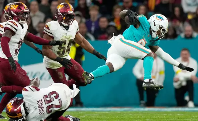 Miami Dolphins wide receiver Malik Washington (6), top right, is tackled by Washington Commanders safety Darnell Savage (25) during the second half of an NFL football game between the Washington Commanders and the Miami Dolphins in Madrid, Spain, Sunday, Nov. 16, 2025. (AP Photo/Bernat Armangue)