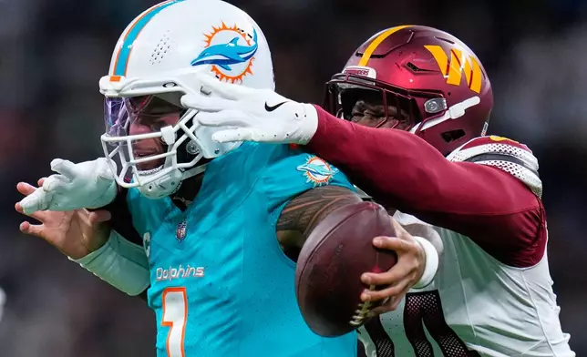 Miami Dolphins quarterback Tua Tagovailoa (1) is tackled by Washington Commanders linebacker Von Miller (24) during the second half of an NFL football game between the Washington Commanders and the Miami Dolphins in Madrid, Spain, Sunday, Nov. 16, 2025. (AP Photo/Manu Fernandez)