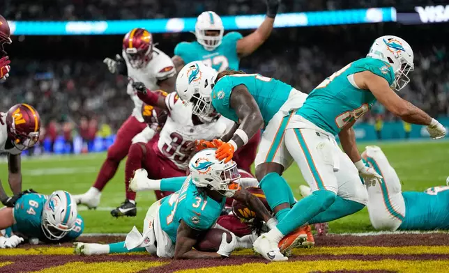 Miami Dolphins running back Ollie Gordon II (31), center, scores a touchdown during the second half of an NFL football game between the Washington Commanders and the Miami Dolphins in Madrid, Spain, Sunday, Nov. 16, 2025. (AP Photo/Bernat Armangue)