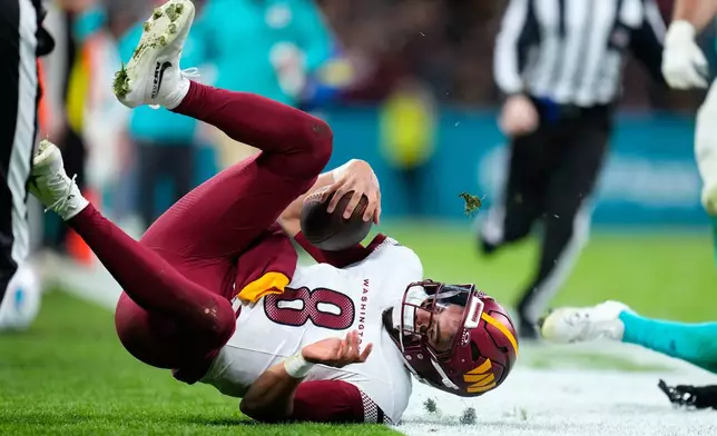 Washington Commanders quarterback Marcus Mariota (8) goes to ground after scrambling for a first down during the second half of an NFL football game between the Washington Commanders and the Miami Dolphins in Madrid, Spain, Sunday, Nov. 16, 2025. (AP Photo/Manu Fernandez)