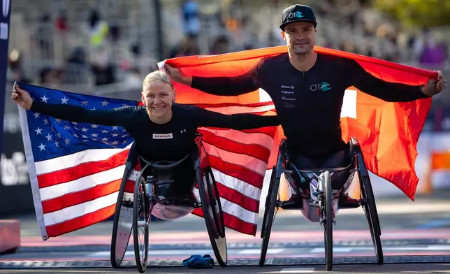 Susannah Scaroni of the United States and Marcel Hug of Switzerland celebrate winning first place in the women's and men's wheelchair divisions of the New York City Marathon, Sunday, Nov. 2, 2025, in New York. (AP Photo/Angelina Katsanis)
