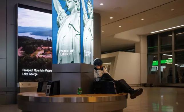 A traveler sleeps at Laguardia International Terminal on Saturday, Nov. 8, 2025, in New York. (AP Photo/Olga Fedorova)