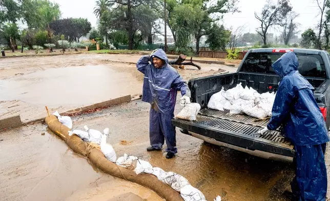 Ronald Jones surveys a property scorched in the Eaton Fire while placing sandbags to prevent mud and water runoff Altadena, Calif., as the region remains under flash flood warnings on Saturday, Nov. 15, 2025. (AP Photo/Noah Berger)