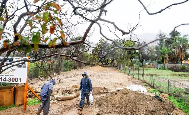James Jones carries sandbags while trying to prevent water from running off a property scorched in the Eaton Fire in Altadena, Calif., as the region remains under flash flood warnings on Saturday, Nov. 15, 2025. (AP Photo/Noah Berger)